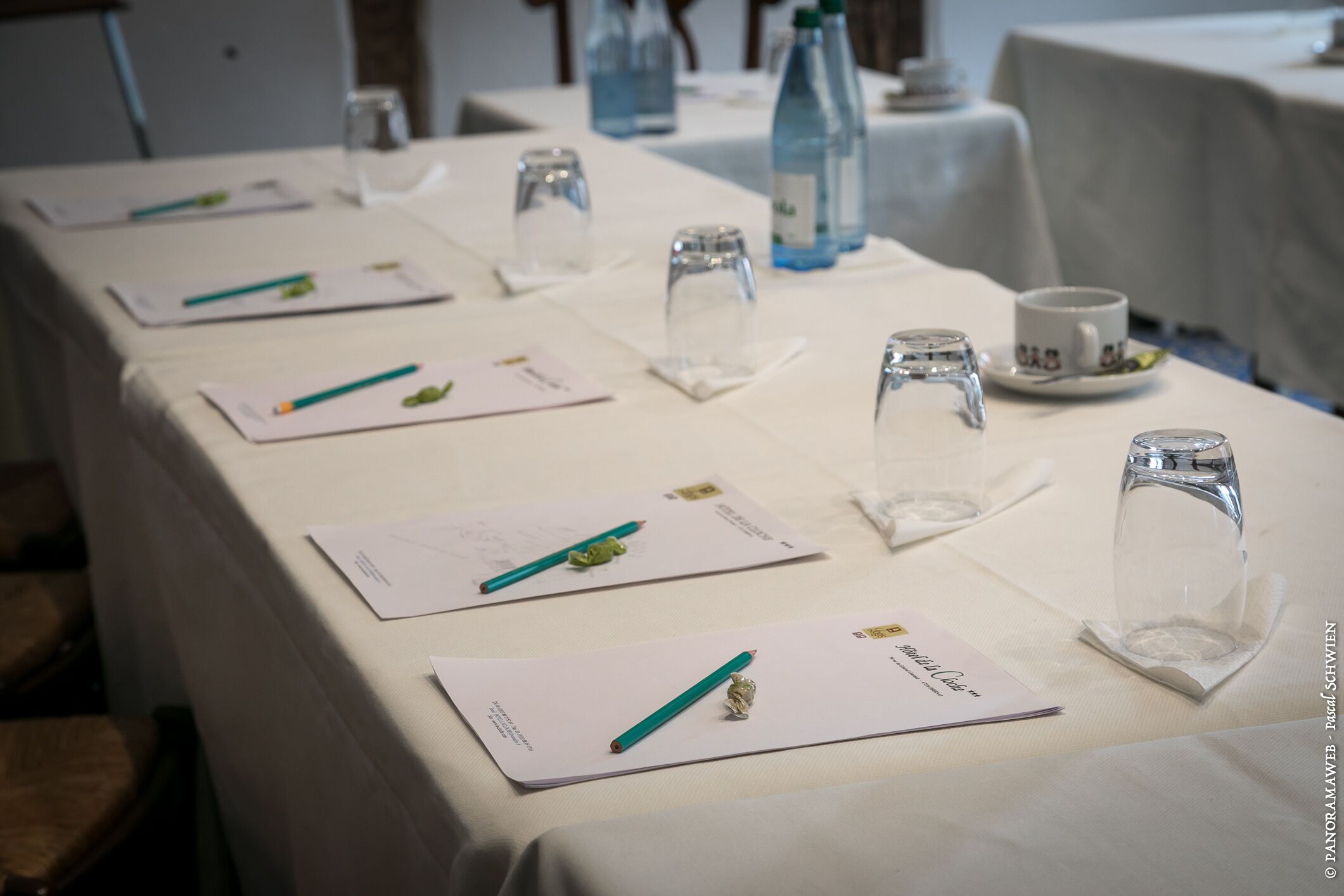A conference table with documents, pens, and glassware.