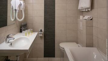 A modern bathroom with a sink, mirror, toilet, and bathtub.