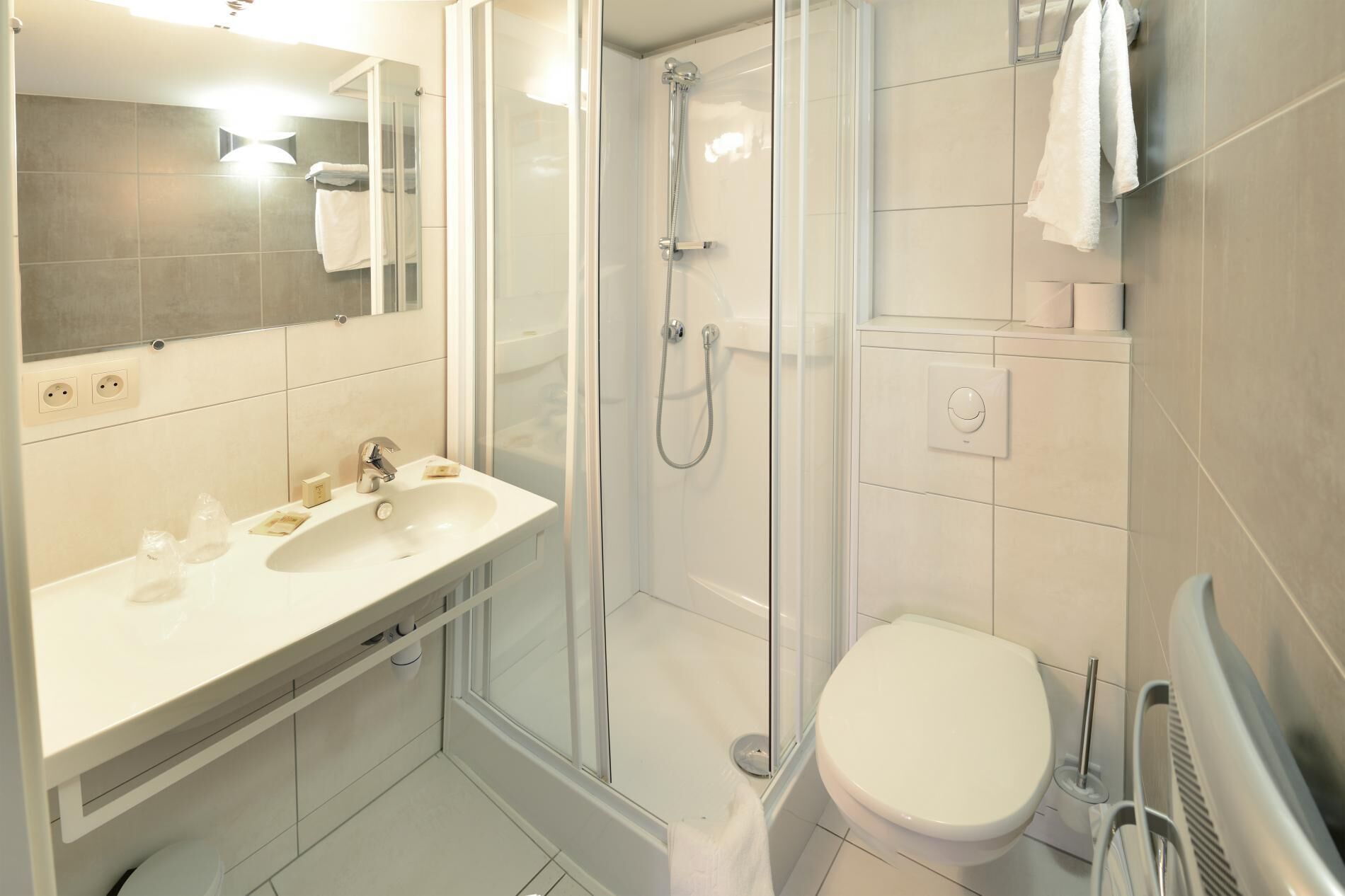 A modern bathroom with a glass-enclosed shower, a white sink, and a toilet.