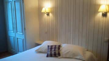 Une chambre d’hôtel avec un lit, deux lampes fixées au mur et une armoire.
