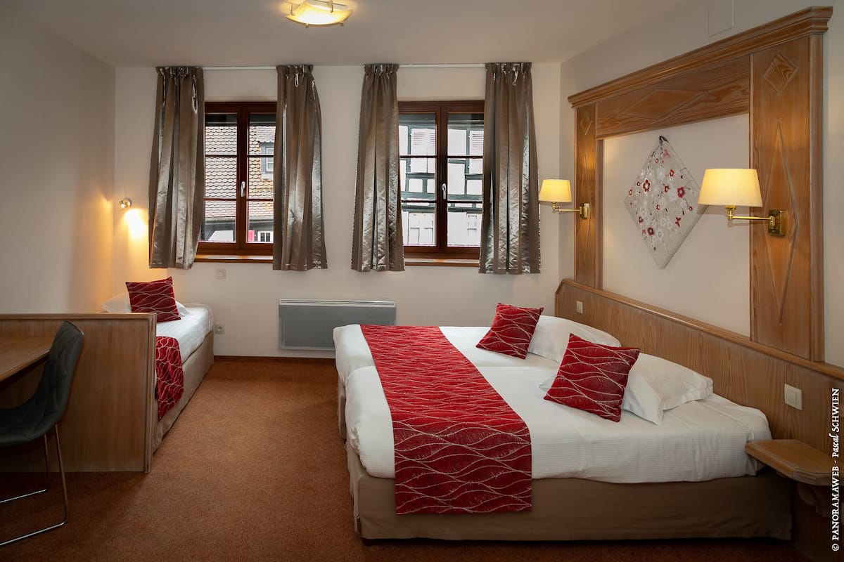 A hotel room with two beds, a desk, and a chair.