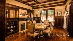 A dining room with a wooden table, chairs, and a fireplace. - Morgan and Wells B&B (Shelby)