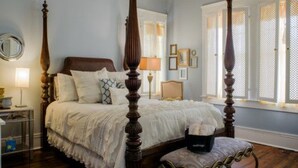 A four-poster bed in a bedroom with a large window and a nightstand with a lamp. - Morgan and Wells B&B (Shelby)