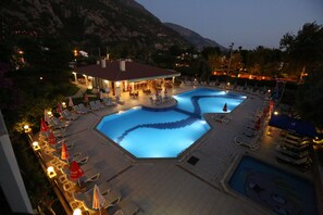 A resort pool area with multiple pools, lounge chairs, umbrellas, and a building with outdoor seating. - Mavruka Hotel (Fethiye)