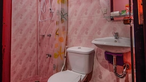 Une salle de bain équipée de toilettes, d’un lavabo et d’une douche avec un rideau de douche à motifs floraux.