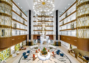 A multi-level hotel lobby with a central seating area, multiple floors with balconies, and a modern chandelier. - Calido Sol Hotel - All inclusive (Alanya)
