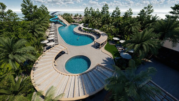 A resort with a large, winding pool surrounded by palm trees and lounge areas. - Calido Sol Hotel - All inclusive (Alanya)