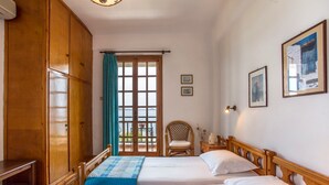 Habitación con dos camas, armario de madera y ventana con cortinas.