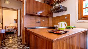 A kitchen with wooden cabinets, a tiled backsplash, and a countertop with a kettle and a magazine.