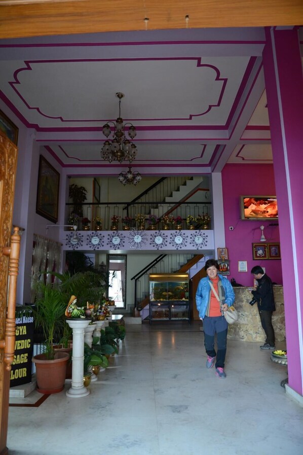A lobby with a staircase, potted plants, and a chandelier. - A Palace on River - Rashmi guest House (Varanasi)