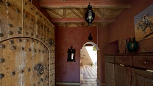 A hallway with a wooden door, a tiled floor, and a painting on the wall. - Kasbah La Cigogne (Aït Benhaddou)