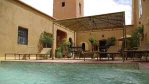 A pool area with lounge chairs and a covered seating area. - Kasbah La Cigogne (Aït Benhaddou)