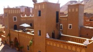 A traditional building with multiple balconies, a spiral staircase, and a view of the surrounding landscape. - Kasbah La Cigogne (Aït Benhaddou)