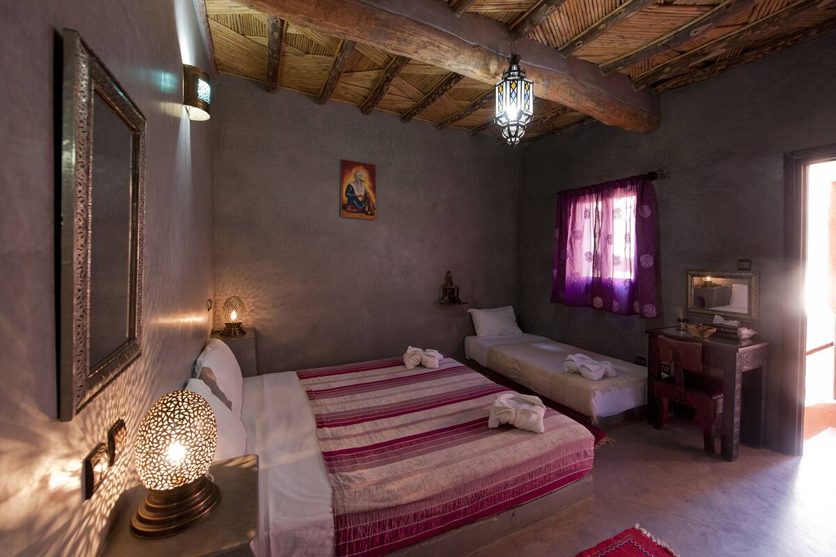 A bedroom with a bed, bedside table, lamp, and a window with curtains.