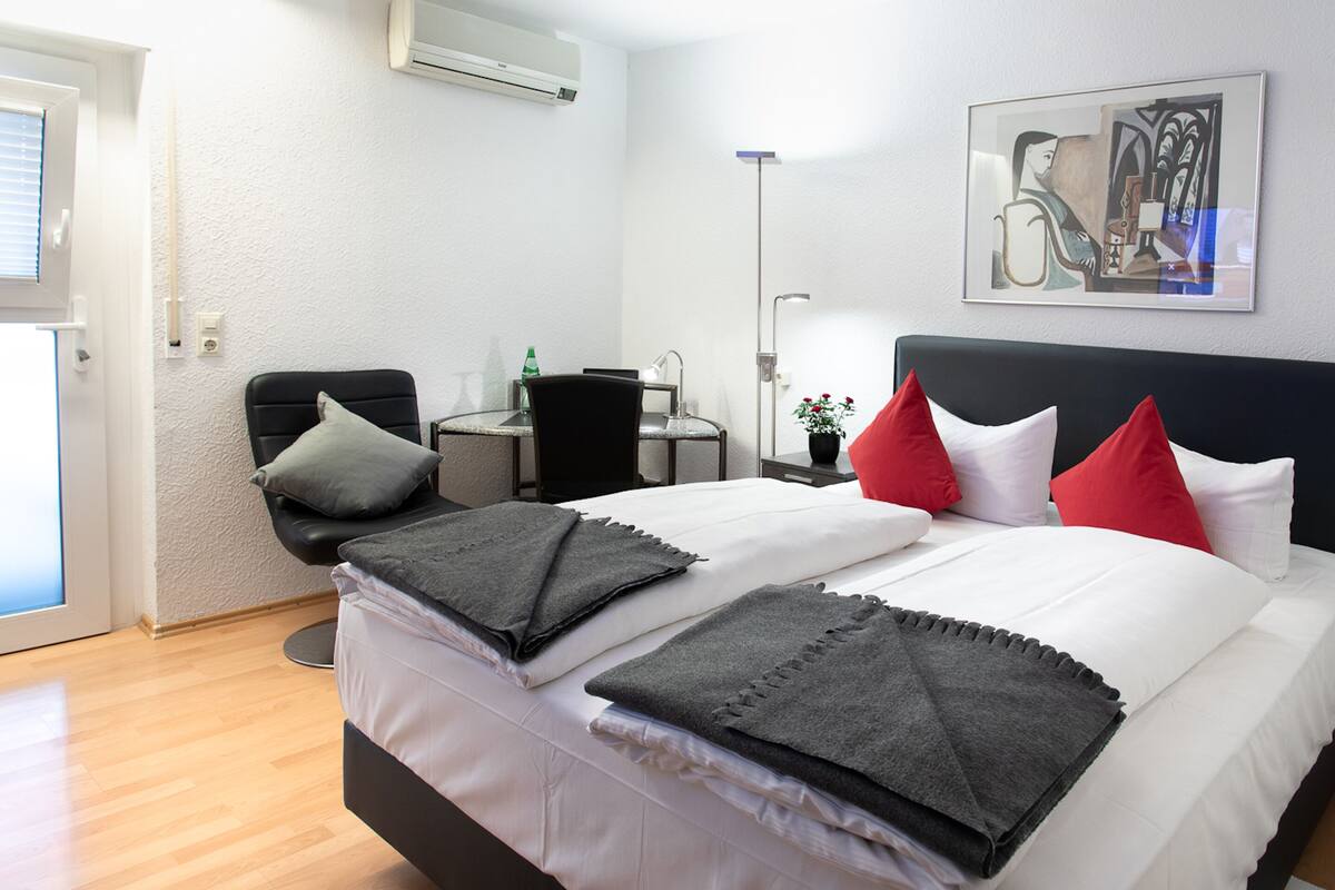 Ein Hotelzimmer mit Bett, Schreibtisch, Stuhl und einem Bild an der Wand.