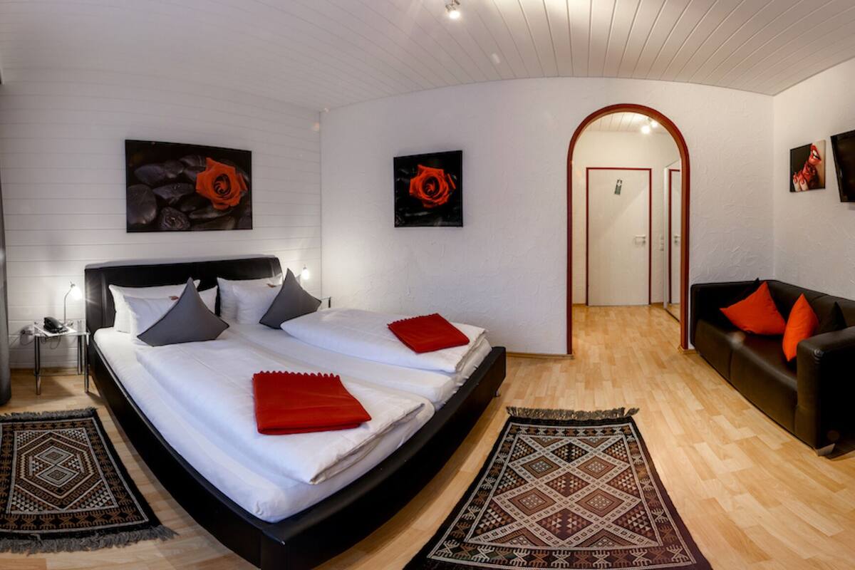Ein modernes Hotelzimmer mit einem großen Bett, einer Sitzecke, einem Essbereich und einem Fernseher.
