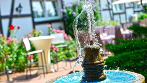 Une fontaine dont l’eau jaillit d’une colonne centrale, entourée d’un bassin circulaire en pierre.