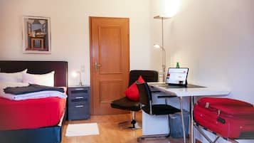 Ein Hotelzimmer mit Bett, Schreibtisch, Stuhl und einem roten Koffer.
