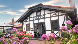 Un bâtiment traditionnel à colombages, doté d’un toit en tuiles, d’une porte et d’un petit porche.