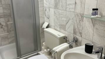 Un bagno con il water, lavandino e zona doccia.