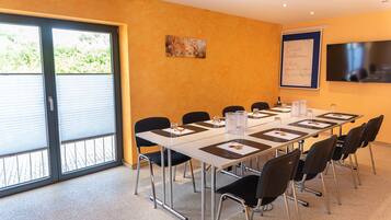 Une salle de conférence avec une longue table, des chaises noires et un tableau blanc au mur.