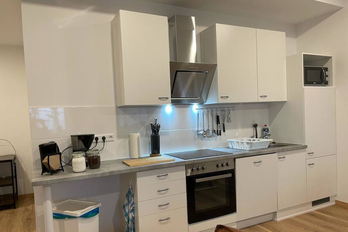 Eine moderne Küche mit weißen Schränken, Edelstahlgeräten und einer Holz Arbeitsplatte.
