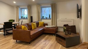Un salon moderne avec un canapé d’angle marron, une table à manger avec des chaises et une petite table basse.