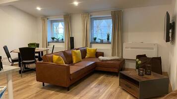 Un salon moderne avec un canapé d’angle marron, une table basse en bois et un coin repas comprenant une table et des chaises.