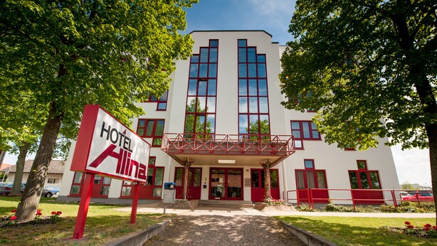 A hotel entrance with a red and white sign, a covered walkway, and a cobblestone path leading to the entrance. - Hotel Alina (Wiesbaden)