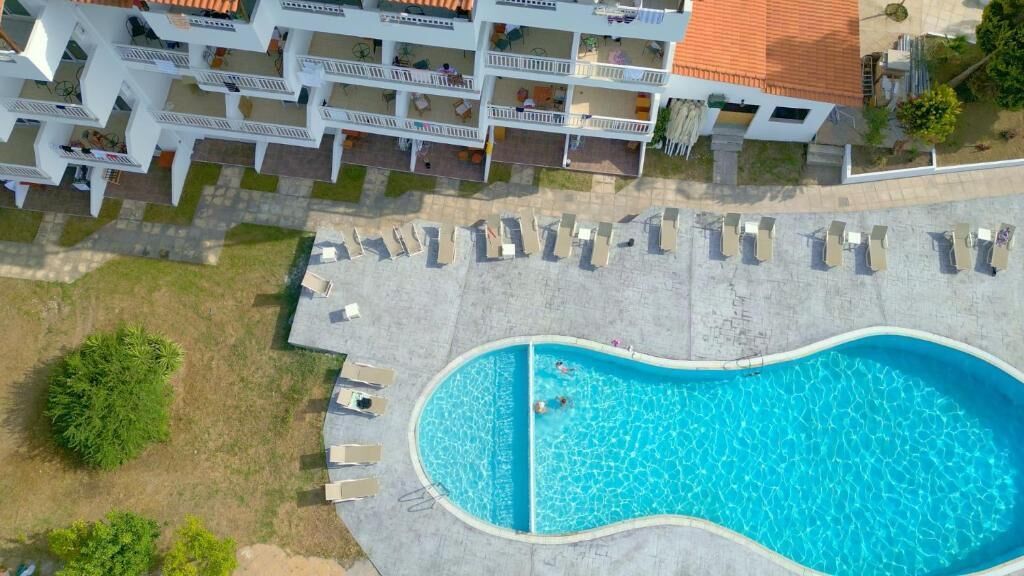 Vista aérea de un hotel con piscina, varios balcones y zonas de estar al aire libre.