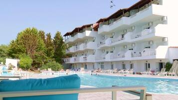 Hotel amb piscina, diversos balcons i cel blau.