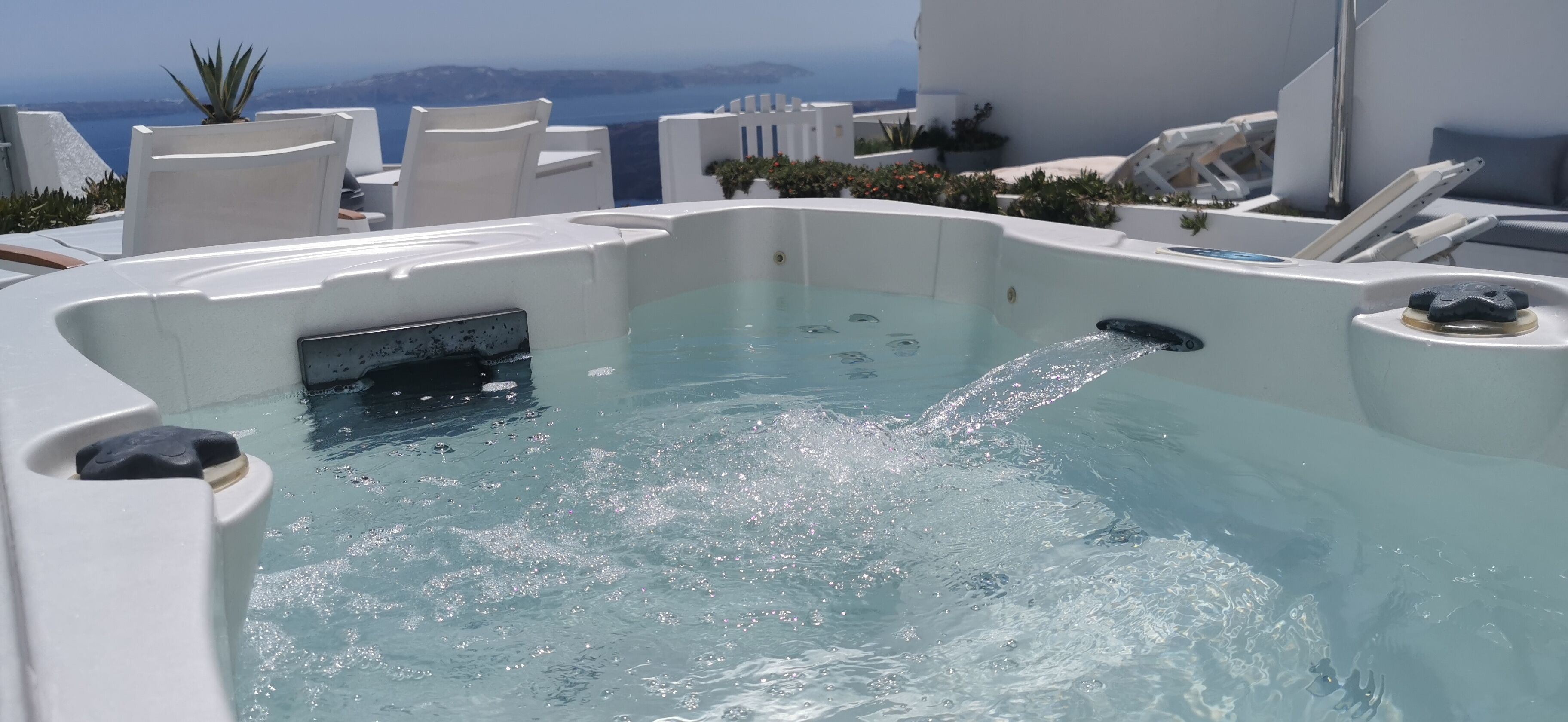 A hot tub with a clear view of the sea and mountains in the background.