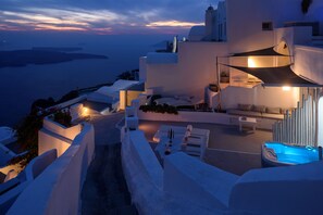 A modern hotel with a pool, outdoor seating, and a view of the sea at dusk. - Zenith Blue Traditional Houses (Santorini)