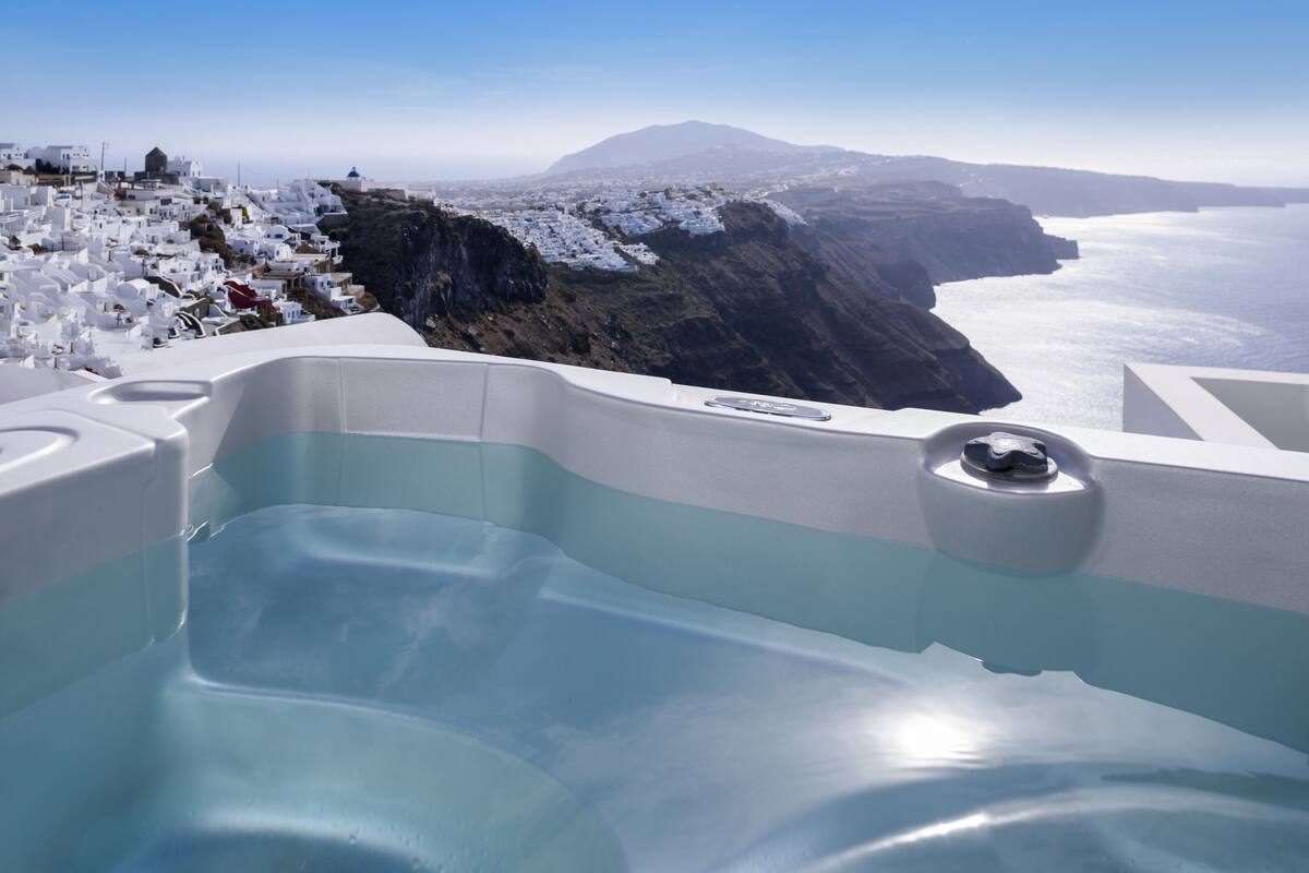 A hot tub with a clear view of a coastal landscape, including a mountain and the sea.