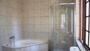 Une salle de bain avec une baignoire, une douche à parois de verre et des toilettes.