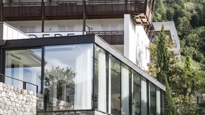 A modern hotel with a stone facade, large glass windows, and a balcony. - Boutique Hotel Belvedere (Naturno)
