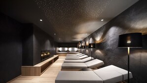 A modern spa with a row of massage tables, wooden benches, and ambient lighting. - Boutique Hotel Belvedere (Naturno)