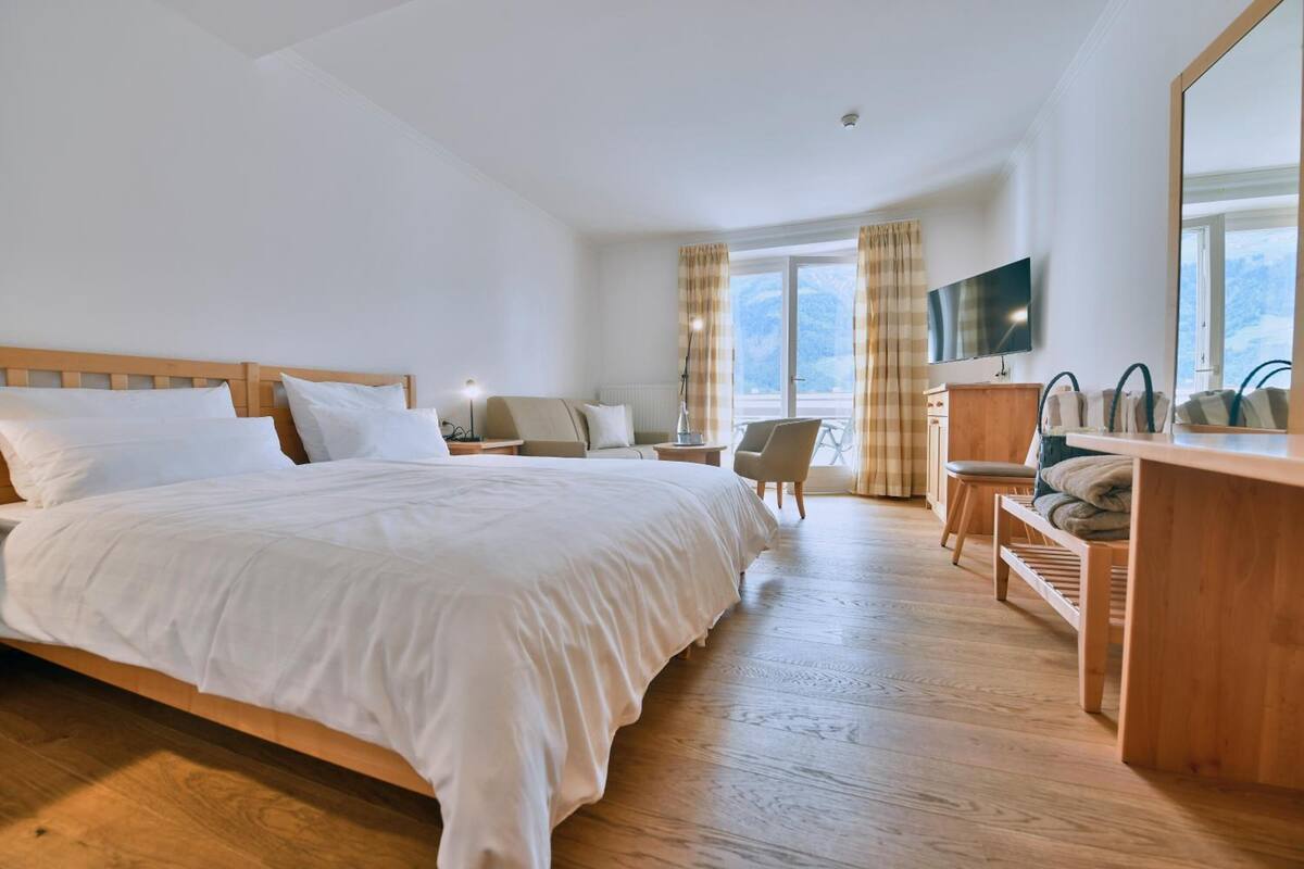 Habitación de hotel con una cama grande, un escritorio, una silla, un televisor y vistas al exterior.
