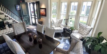 Un salón espacioso con una mesa de centro negra, sillones estampados y un ventanal con vistas al exterior.
