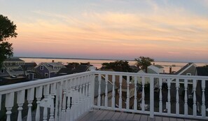 A residential area with a white balcony railing overlooking a body of water during sunset.