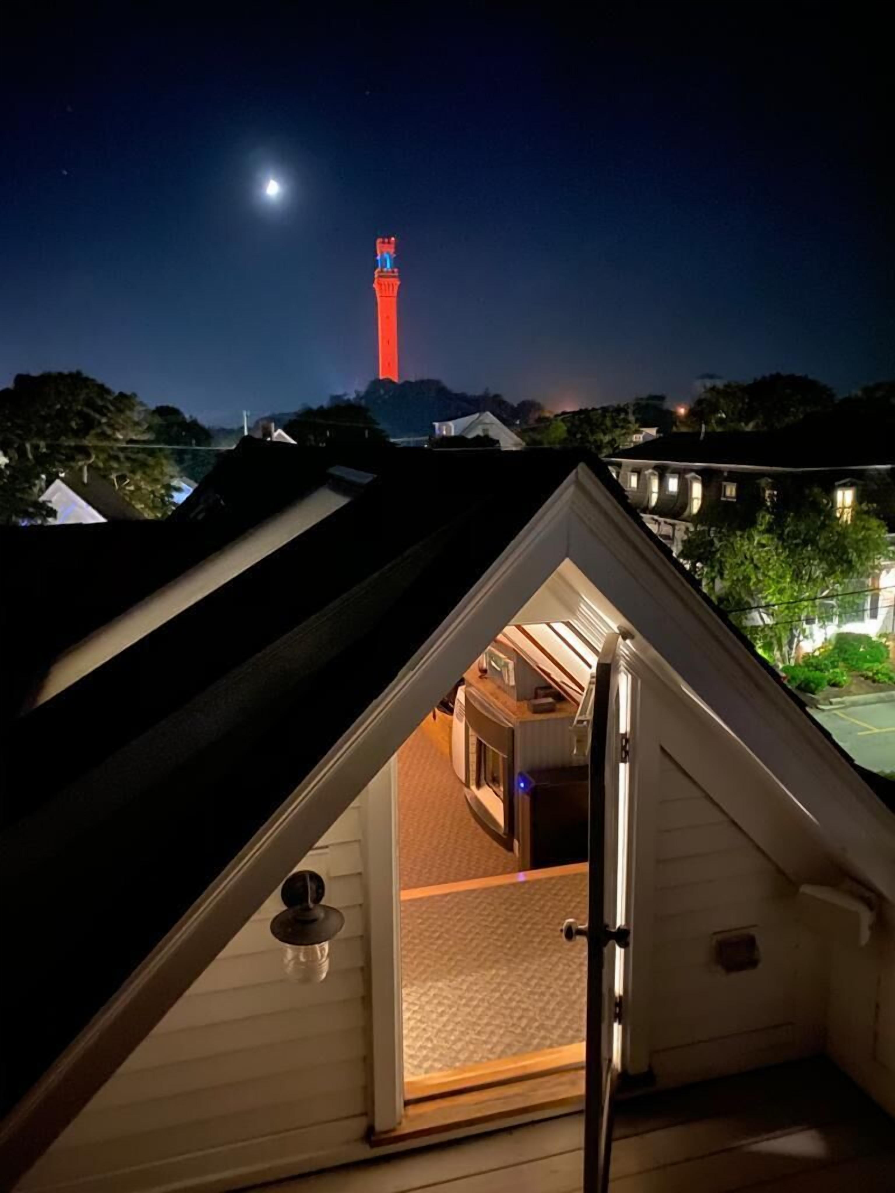 A triangular attic room with a view of a red tower in the distance.