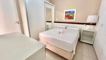 Una habitación de hotel con una cama, una mesita de noche, una lámpara y una obra de arte colgada en la pared.