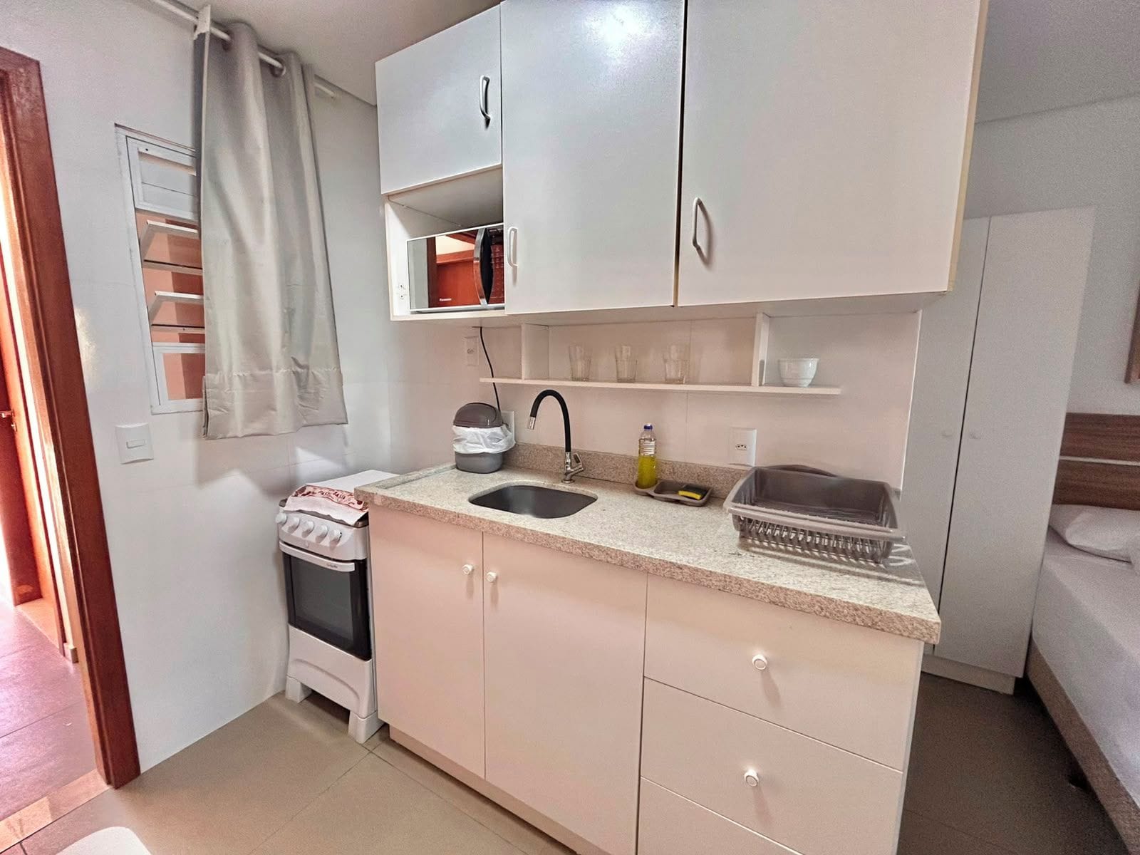 Una kitchenette compacta con estufa, lavamanos y armarios.