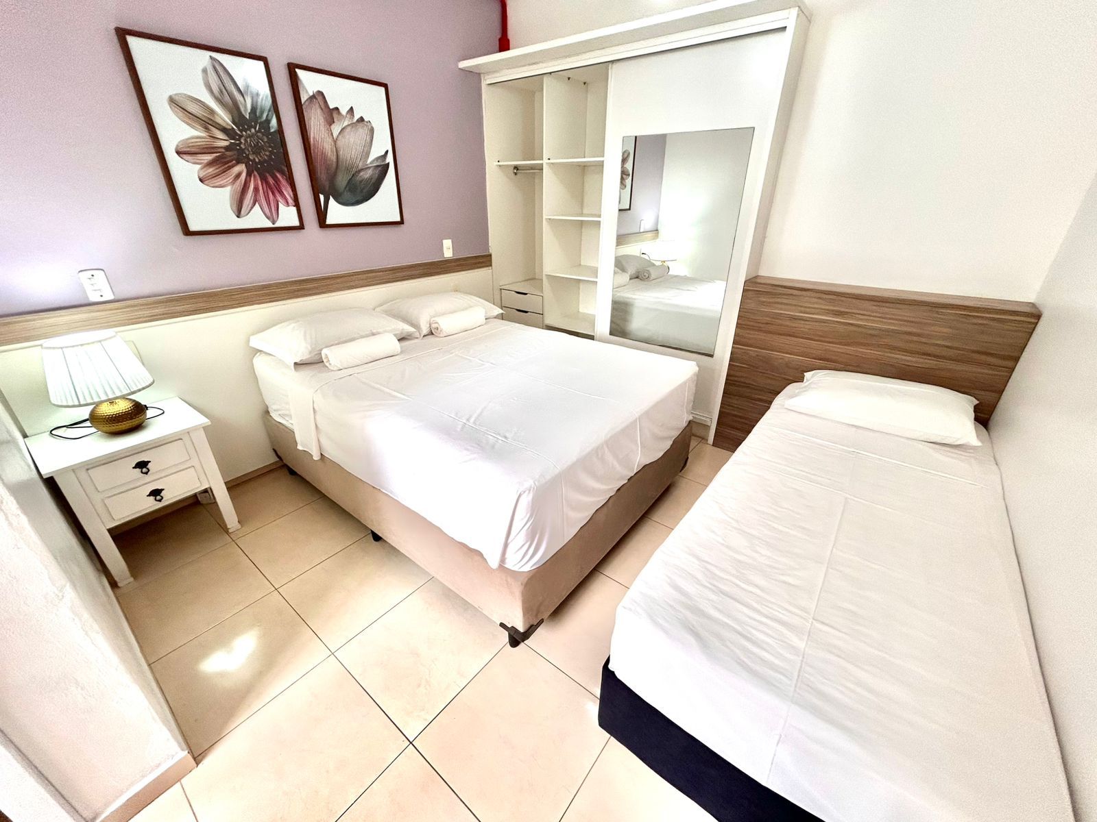 A hotel room with a bed, a nightstand, a wardrobe, and a mirror.