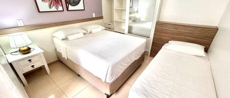 A hotel room with a bed, a nightstand, a wardrobe, and a mirror.