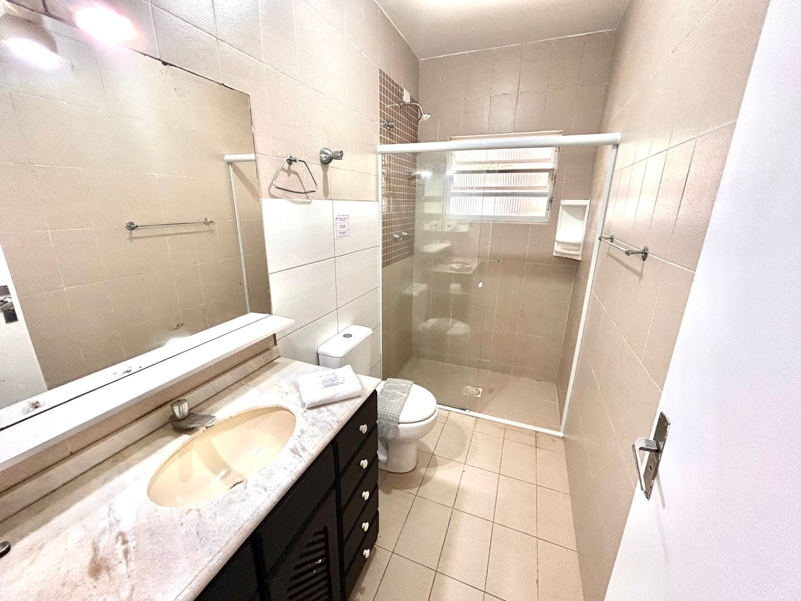 Une salle de bain avec une douche à parois de verre, des toilettes et un lavabo avec un miroir au-dessus.