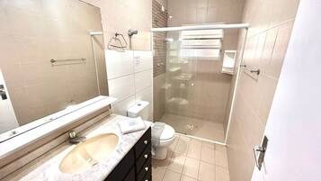 Une salle de bain avec une douche à parois de verre, des toilettes et un lavabo avec un miroir au-dessus.