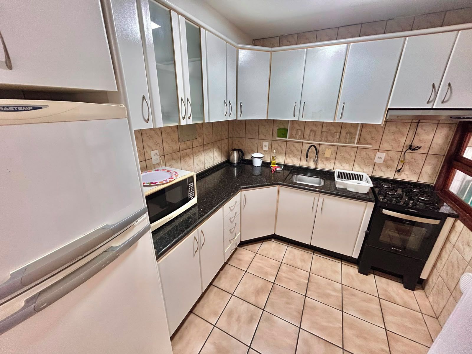 A kitchen with white cabinets, a microwave, a sink, and a stove.