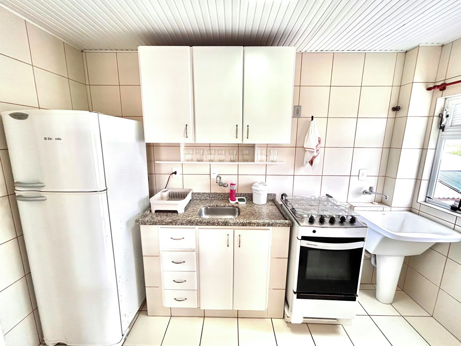 A compact kitchen with a refrigerator, stove, sink, and cabinets.