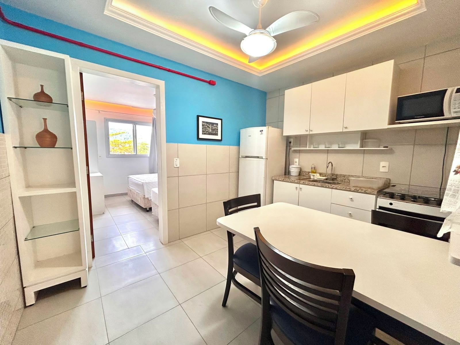 Una cocina compacta con comedor, refrigerador, microondas y ventilador de techo.
